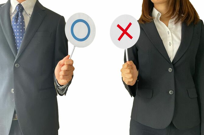 丸とバツの札を持った人