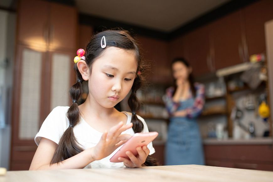 スマホを使用する子供と心配する母親