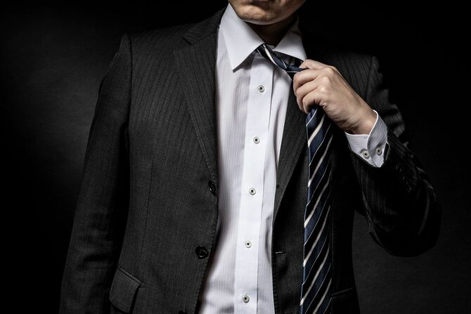 ネクタイを緩めるスーツ姿の男性