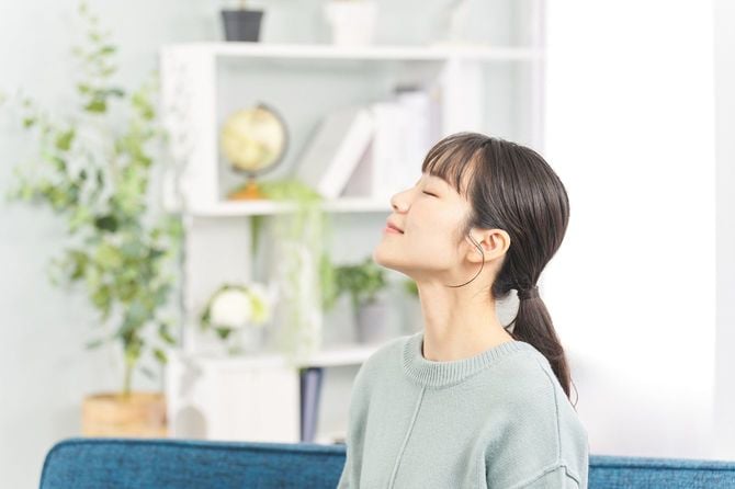 リビングで目を閉じて、深呼吸をしている女性
