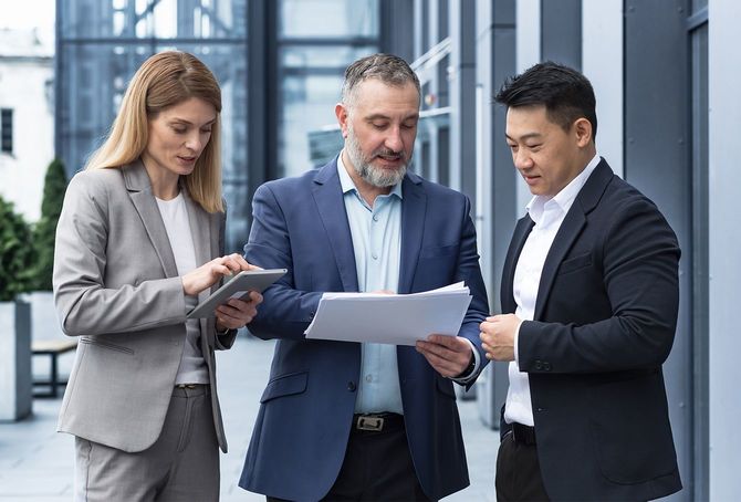 国際ビジネスチーム会議。成熟した男性、白人女性、アジアの従業員がコミュニケーションをとる