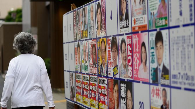 女性が候補者ポスター掲示場の前を通り過ぎていく