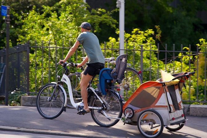 子供をトレーラーに乗せて自転車に乗っている男性