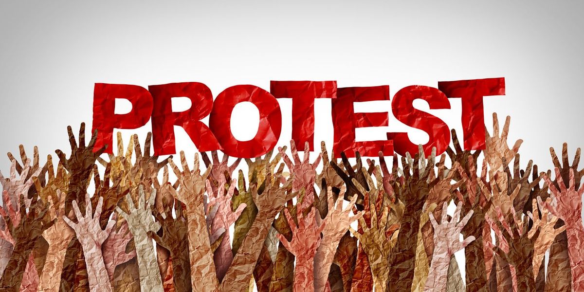 人々の挙げた手の上に「PROTEST」の文字