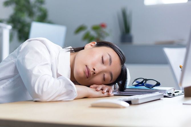 デスクで居眠りする女性