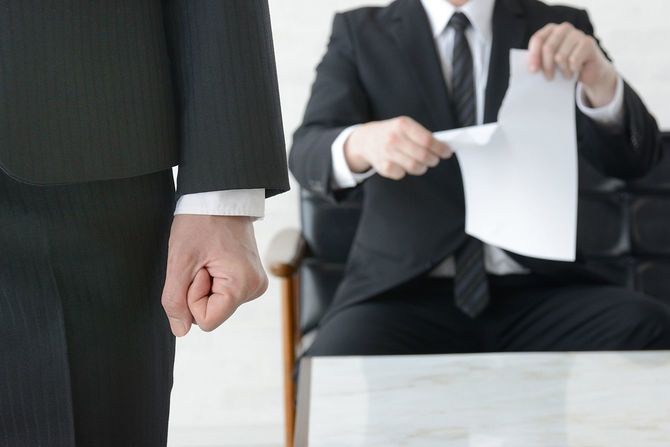 拳を持つ怒っているビジネスマンが強くつかんだ