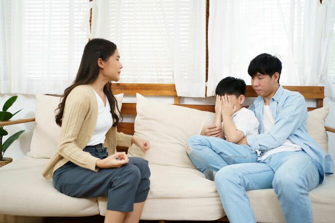 顔を覆う男の子と両隣の両親