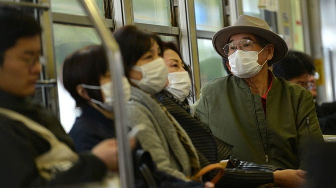 晴れた日の東京を走るバスの乗客たちがマスクを着けている