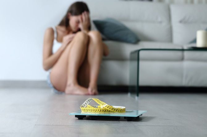悩んでいる人と体重計
