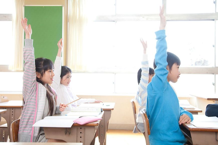 授業中に手を挙げる小学生たち