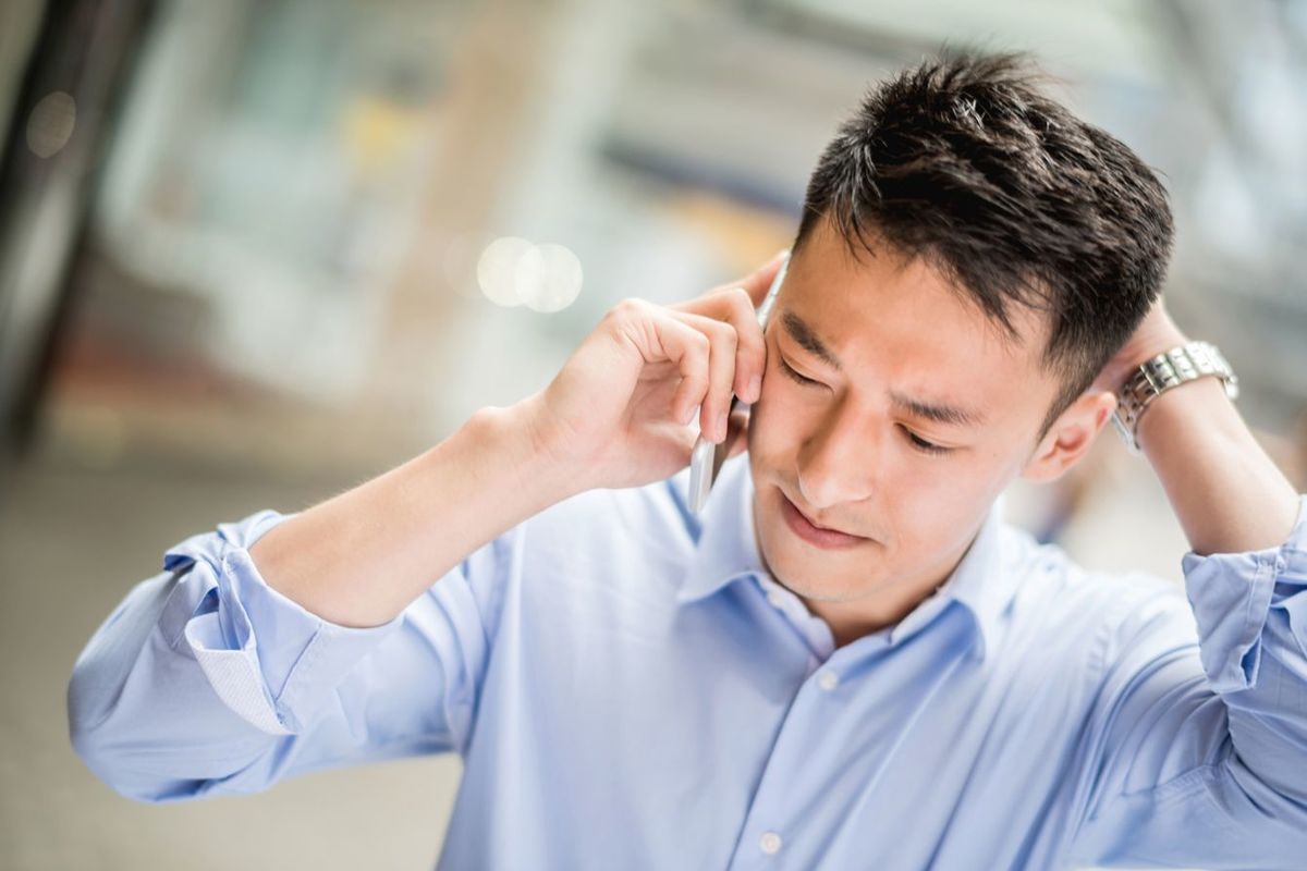 心配顔で電話をしている男性