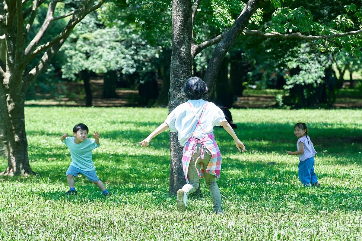 公園で走り回る子供たちを追いかける女性