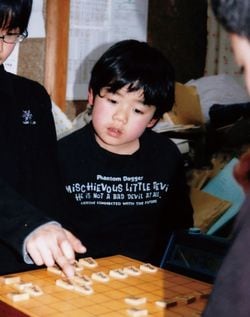 上級生の対局を興味深そうにのぞき込む藤井三冠。