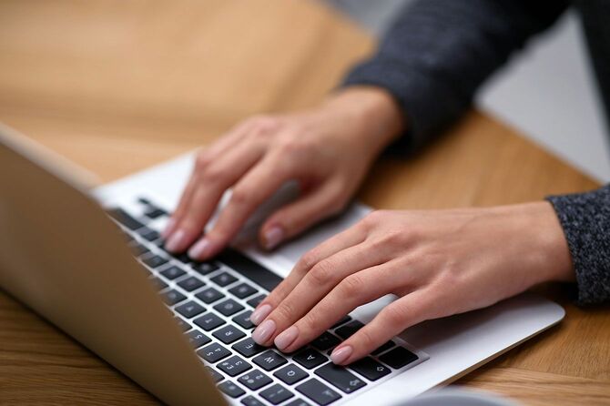 パソコンのキーボードを打つ女性の手