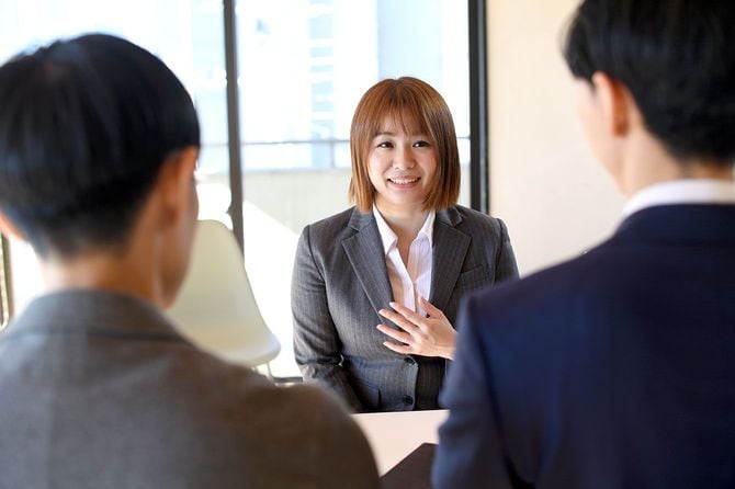 オフィスで男性インタビュアーの質問に答えるスーツ姿の女性