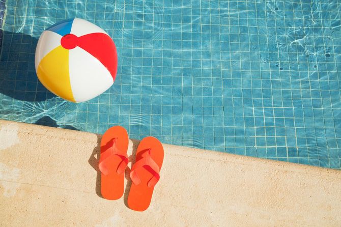 プールサイドにサンダル、プールにはカラフルなボール