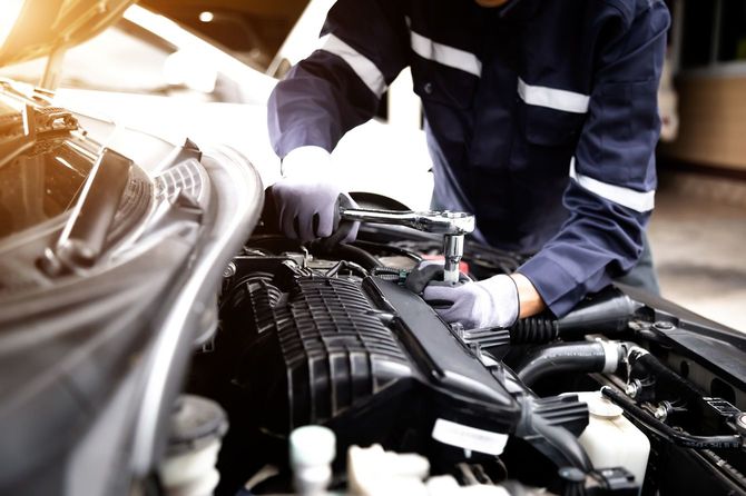 メカニックガレージで車のエンジンに取り組む自動車整備士