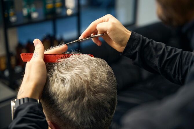 理髪店で床屋から散髪を受ける男性