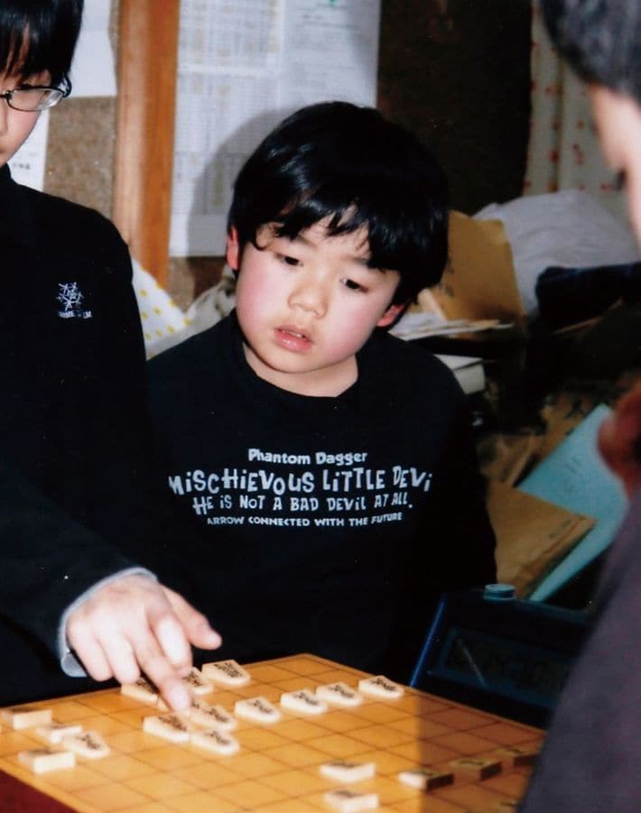上級生の対局を興味深そうにのぞき込む藤井三冠。（画像＝『藤井聡太　天才の育て方』より）