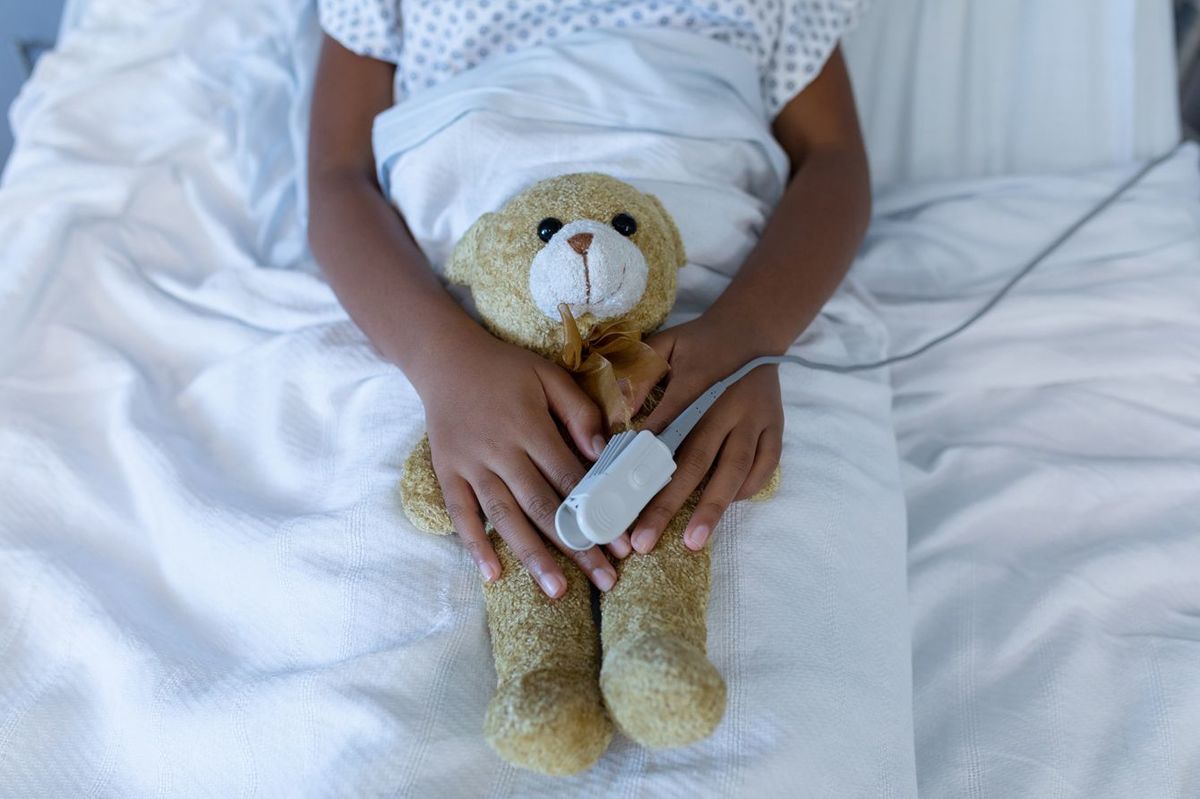 病院のベッドでパルスオキシメーターを着けている子供