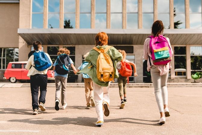 スクールバスを降りて学校に駆け出す子供たち