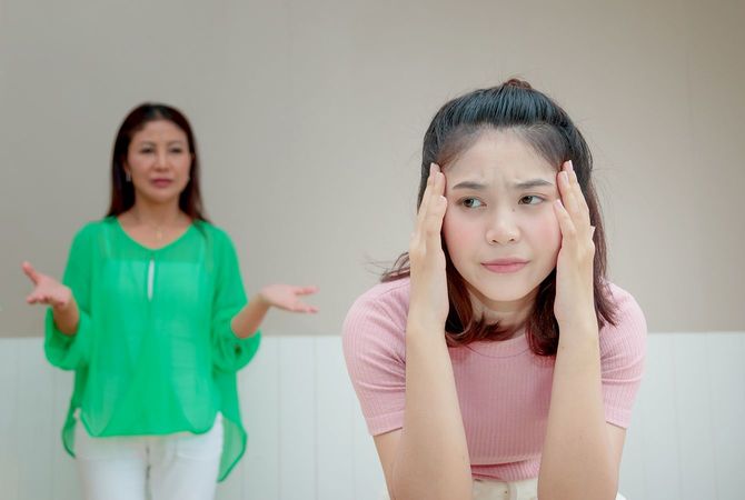 怒った母親は、何か不平を言っている娘の後ろに立っています。