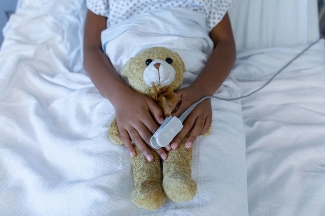 病院のベッドでパルスオキシメーターを着けている子供