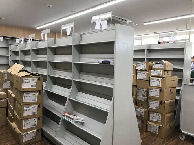 オープン前の「ほなび」の店内。空っぽの書棚の前に本の入った段ボールが積み重なる