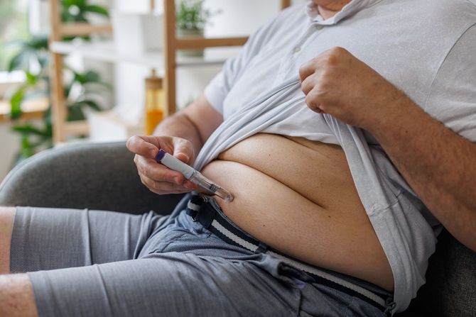 腹部にインスリンを自分で打っている肥満体型の男性