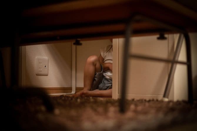 机の下に隠れている少年