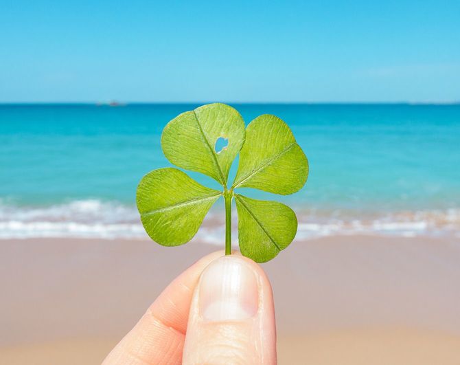 青い海にかざした四つ葉のクローバー