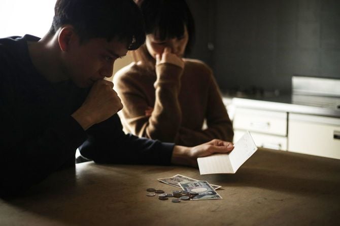 通帳を見て心配する夫婦
