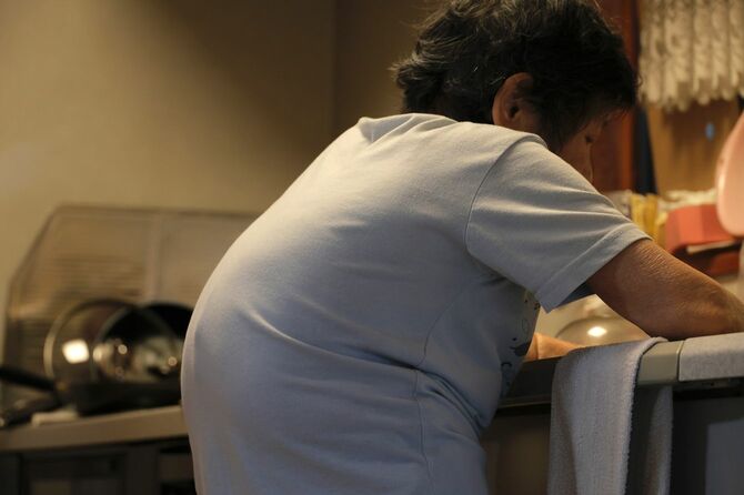 台所で作業をしている腰の曲がったシニア女性
