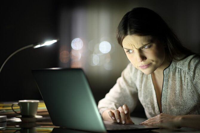 夜、ノートパソコンで不審なコンテンツをチェックしている女性