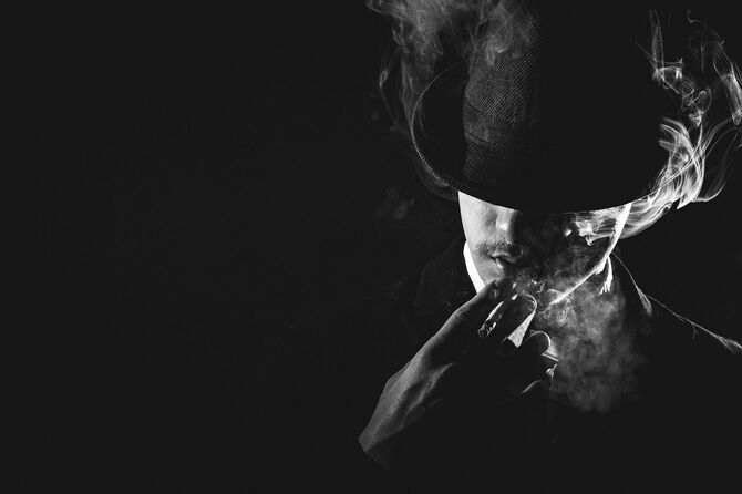 たばこを吸っている黒い帽子をかぶった男
