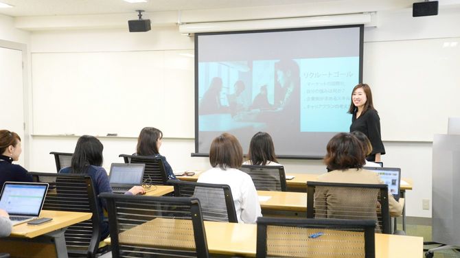 女性が壇上に立つビジネスセミナー