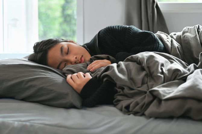 ベッドで眠る10代の女性