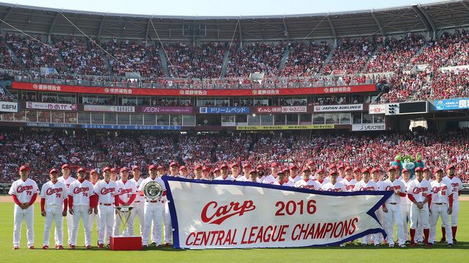 セ・リーグ優勝報告会で、チャンピオンフラッグを手にファンと記念撮影する広島の選手ら＝2016年11月5日、マツダスタジアム