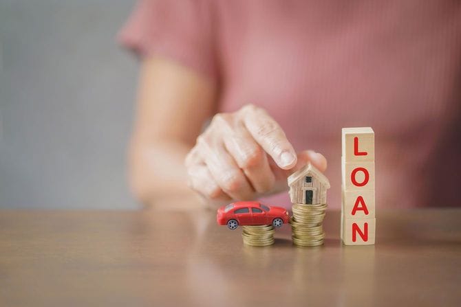 コインの上にのせたミニチュアの車と家、その横に「ローン」の文字