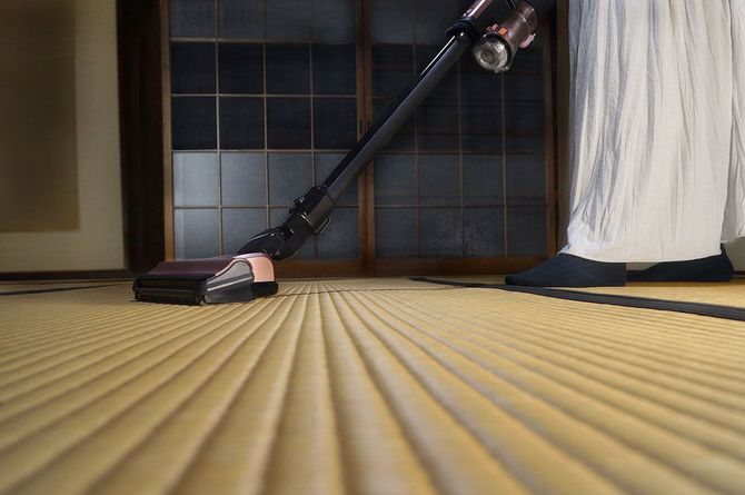 畳の部屋に掃除機をかける人