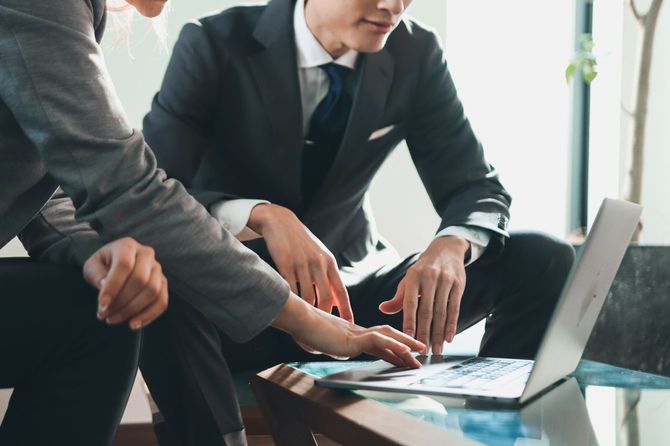 ノートパソコンを使用しながら議論する2人の男性