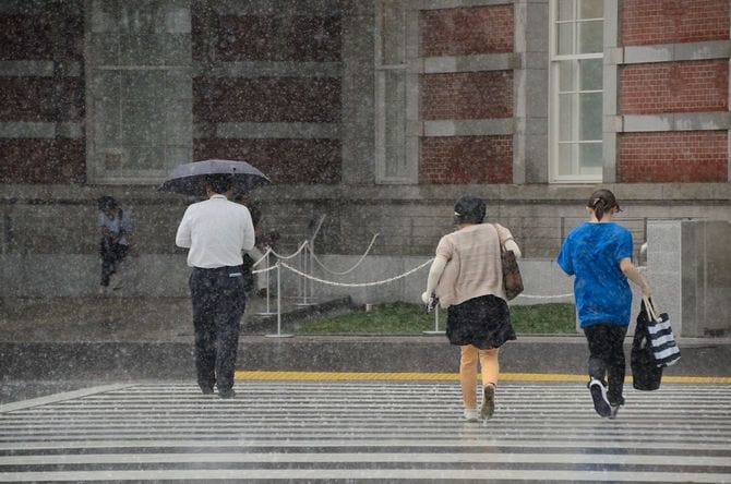 大雨の中、東京駅に向かって走る人々