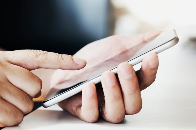 デスクでスマホを使用する男性の手元