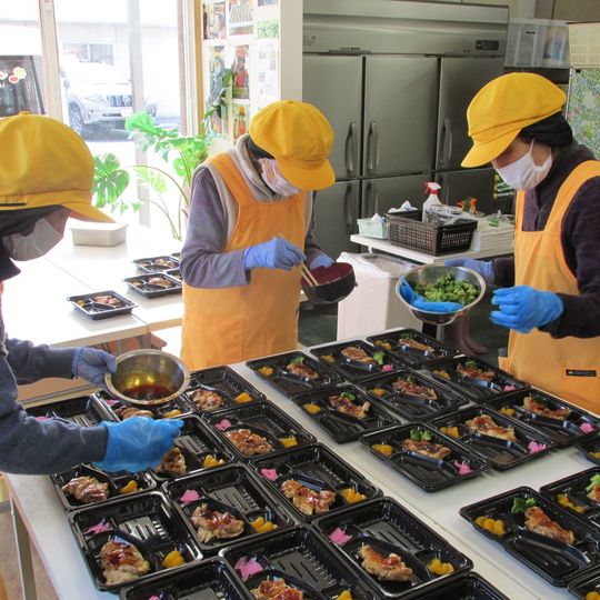 立って盛り付けをするデイサービス利用者たち