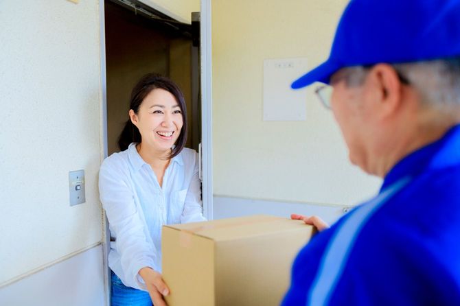 配達員から荷物を受け取る女性