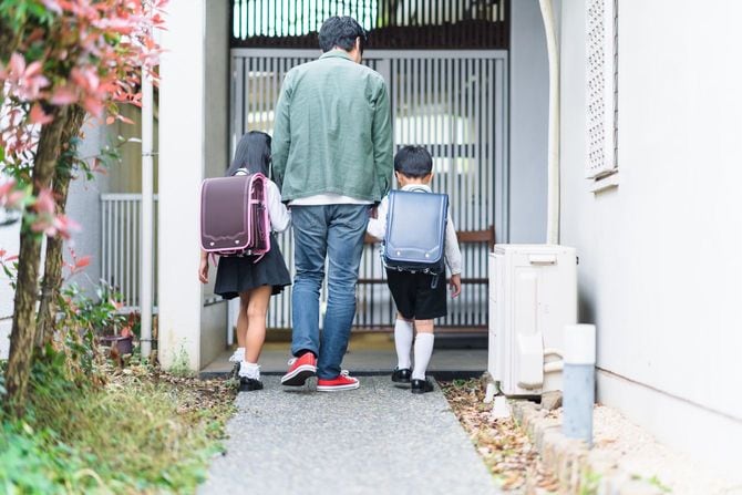 子供たちを学校から家に連れて帰る父親