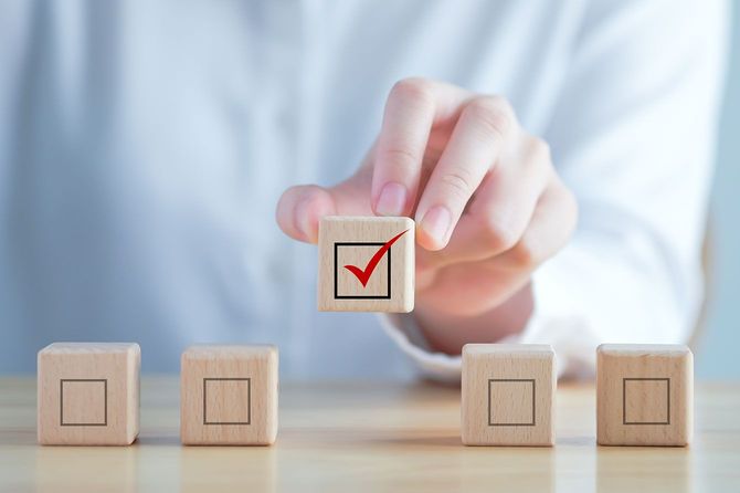 赤いチェックマーク入りの木製ブロックを持つ手