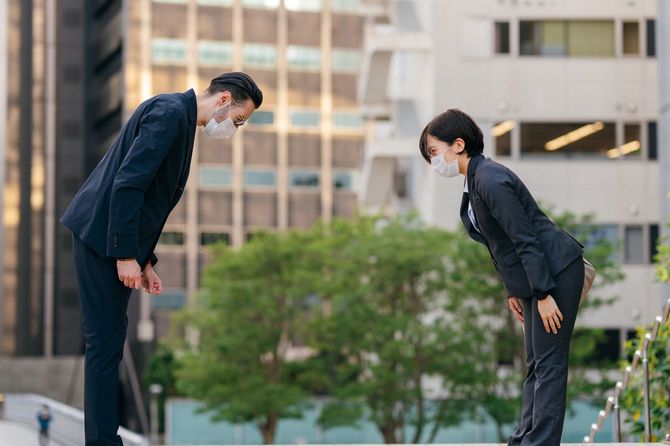 挨拶のためにお辞儀をする2人のビジネスパーソン