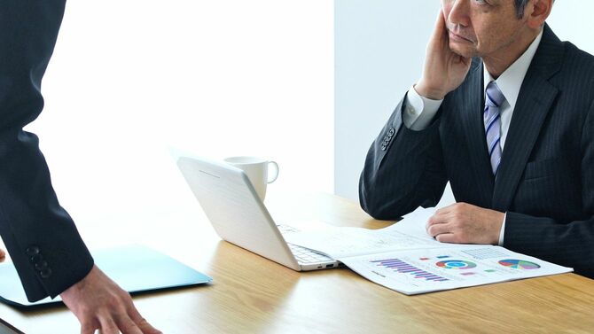 部下の報告を受ける不満げな上司