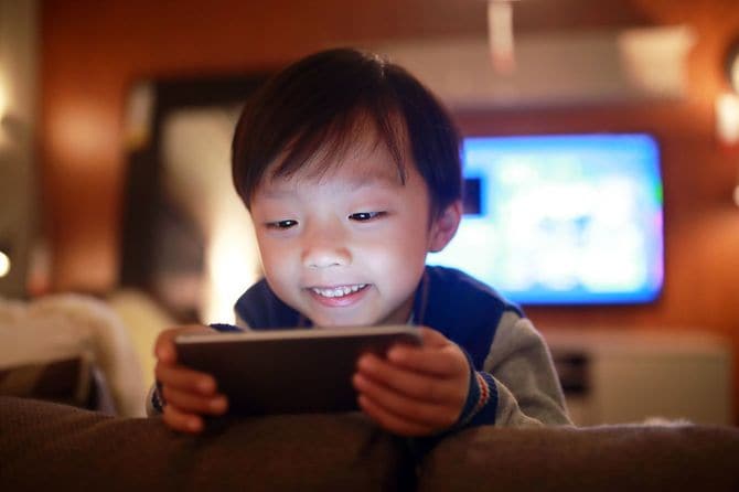 テレビに背を向け、スマホに夢中になる男児